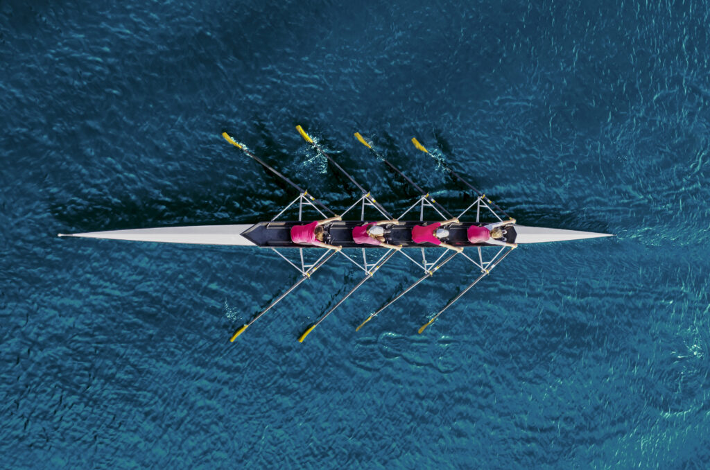4 people rowing a boat on open water